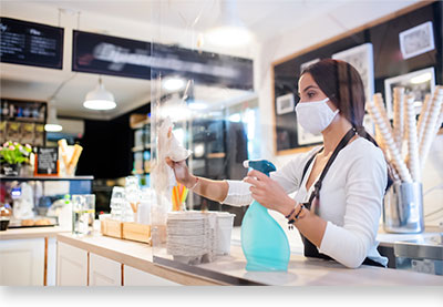 woman cleaning plexiglass over store display counter